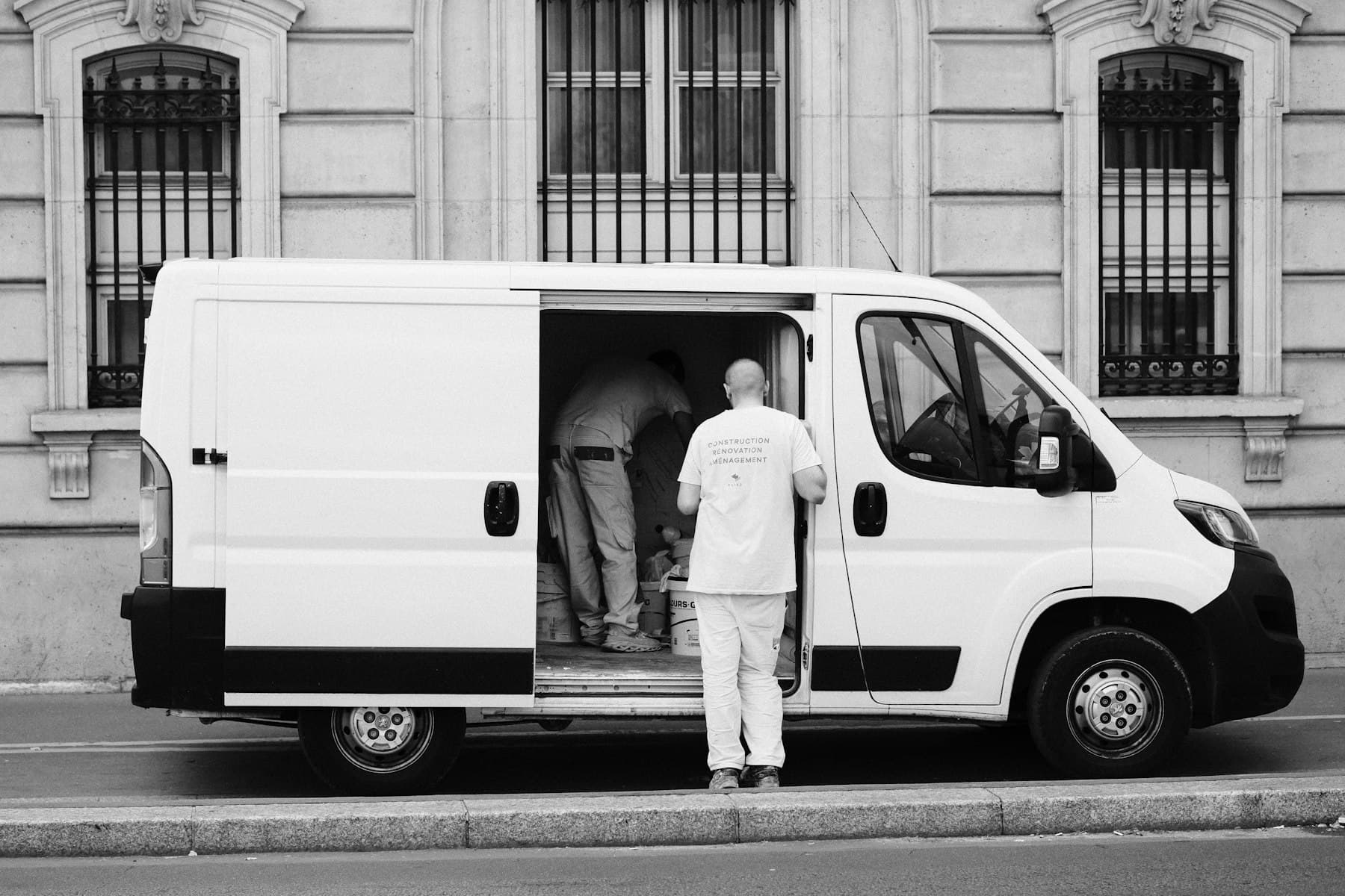 Chauffeur chargeant son utilitaire devant un immeuble parisien, en début de tournée