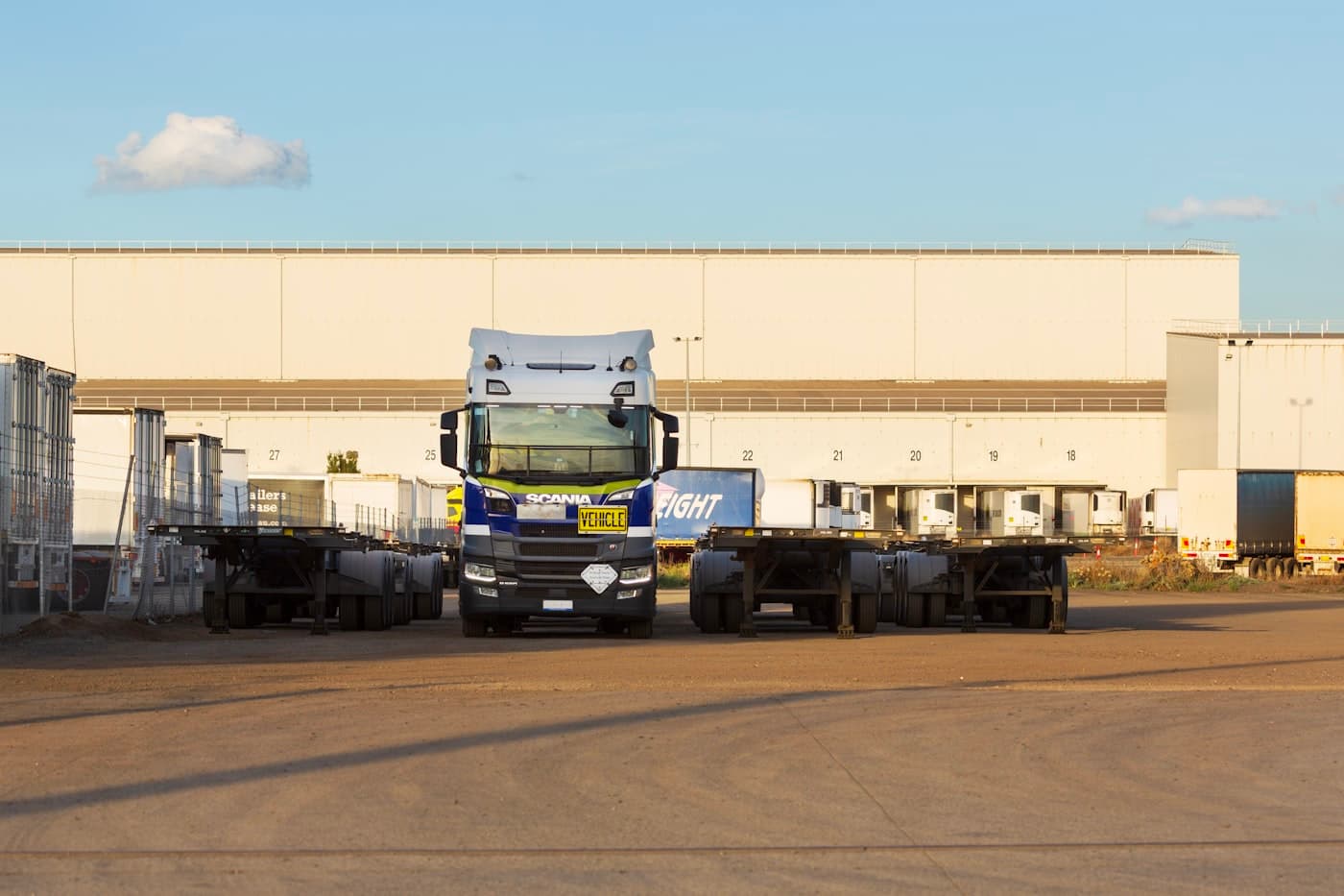 Tracteur routier et châssis porte-conteneurs devant les quais d'un entrepôt